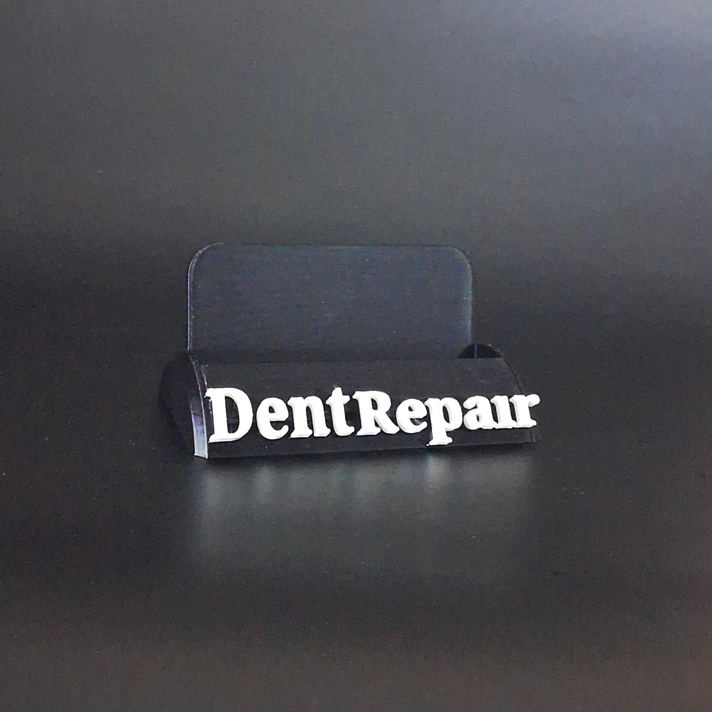 A business card holder that says Dent Repair in bold letters on the front of the display