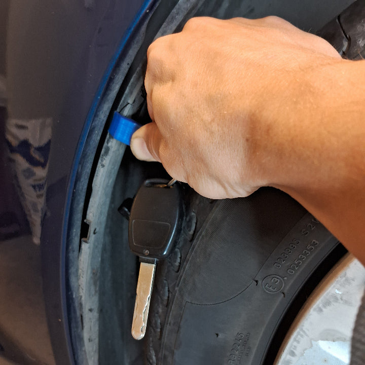 A car fender liner being pushed by a tool to gain access for paintless dent repair