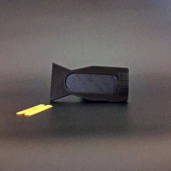 A plastic razor scraper for removing PDR glue photographed on its side with the plastic razor blade removed