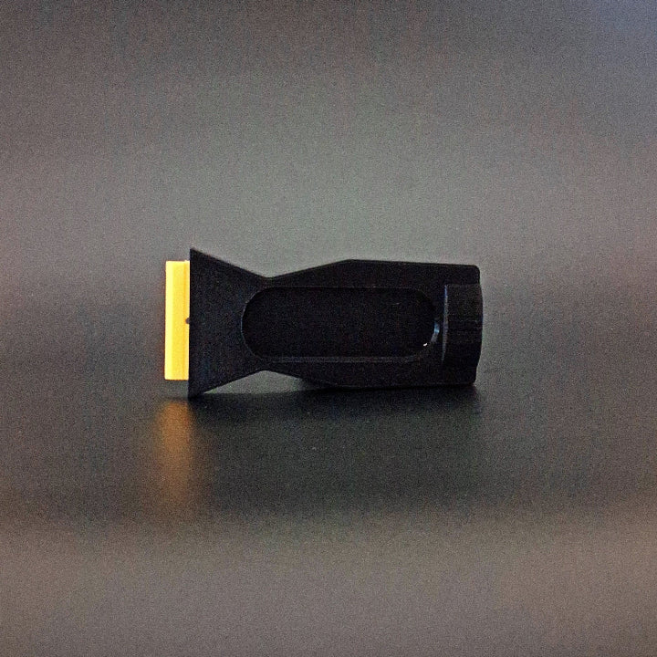 A plastic razor scraper for removing PDR glue photographed on its side
