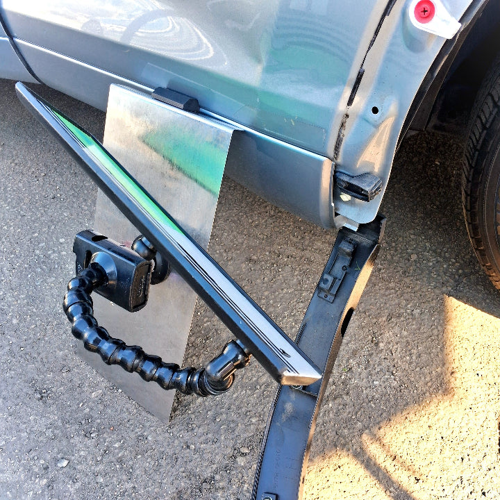 A PDR window guard being used to hold a Paintless Dent Repair light so that a dent can be removed from the bottom of a car door