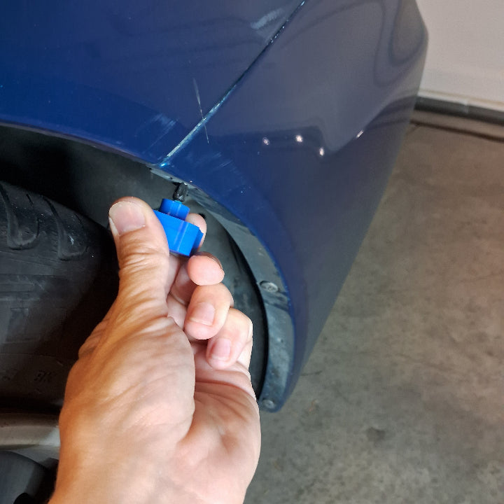 using a small screwdriver tool to remove a quarter panel screw on a car bumper