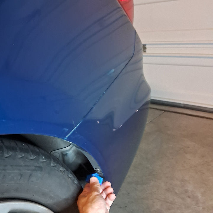 Using a small screwdriver tool to remove a screw on a bumper
